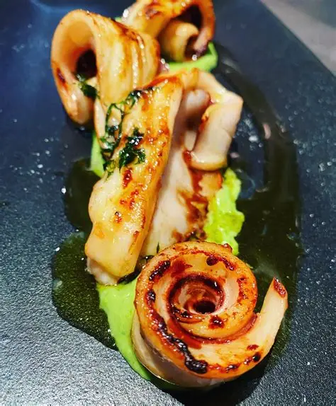 Grilled calamari with herb purée on a dark plate